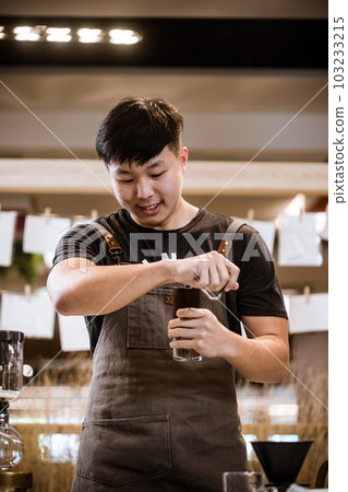 Professional coffee maker - Barista using coffee siphon brewing hot espresso at coffee shop coffee brewing syphon alternative method. Startup Business Concept. Professional coffee maker - Barista using coffee siphon brewing hot espresso at coffee shop coffee brewing syphon alternative method. Startup Business Concept. 103233215