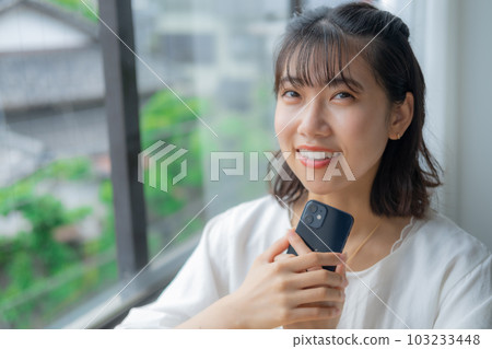 A woman holding a mobile phone A woman holding a mobile phone 103233448