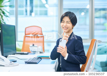 Middle business woman in a suit operating a smartphone in the office 103236537