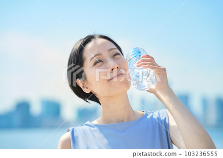 Woman drinking water from a plastic bottle 103236555