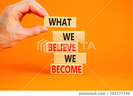 We become or believe symbol. Concept word What we believe We become on wooden block. Beautiful orange table orange background. Businessman hand. Business we become or believe concept. Copy space. 103237248