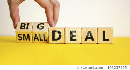 Big or small deal symbol. Businessman turns a wooden cube and changes words 'small deal' to 'big deal'. Beautiful yellow table, white background, copy space. Business and big or small deal concept. 103237255