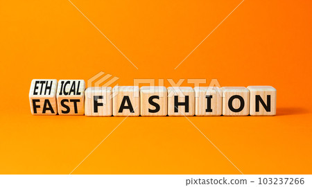 Fast or ethical fashion symbol. Concept words Fast fashion and Ethical fashion on wooden cubes. Beautiful orange table orange background. Business fast or ethical fashion concept. Copy space. 103237266