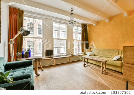 a living room with orange walls and wood flooring, two couches and a coffee table in front of the window 103237502