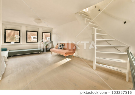 a living room with white walls and hardwood flooring, there is a staircase leading up to the second floor a living room with white walls and hardwood flooring, there is a staircase leading up to the second floor 103237516
