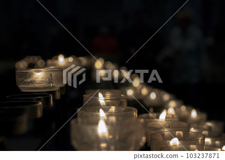 Votive prayer candles inside a catholic church on a candle rack 103237871