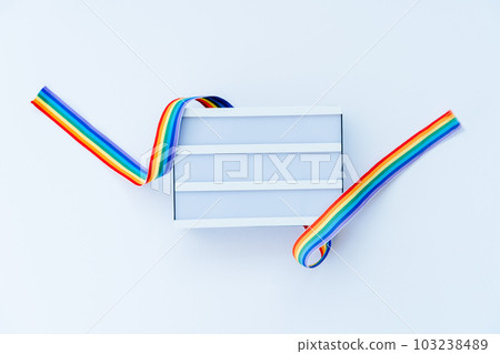 Top view White light box mockup with rainbow LGBT ribbon on a light background isolated. Copy space for text or design. Pride month tape symbol. Gender equality, lgbtq concept. Selective focus. 103238489