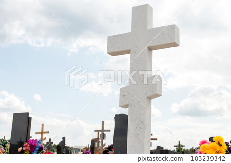 A white marble cross in the cemetery. Tomb decoration. Orthodox cross on the monument A white marble cross in the cemetery. Tomb decoration. Orthodox cross on the monument 103239342