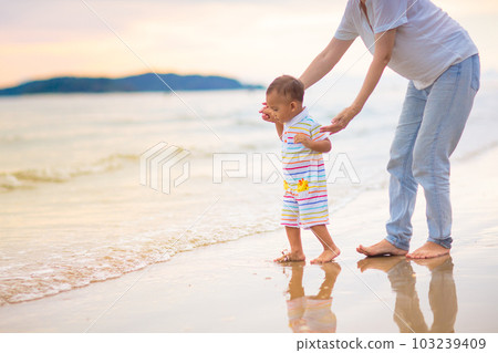 Mother and baby on tropical beach at sunset. 103239409