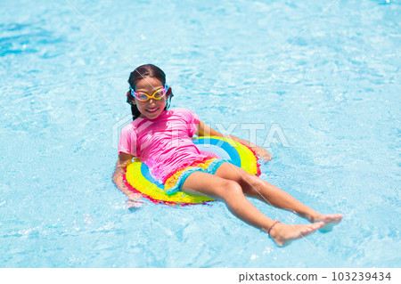 Child in swimming pool on toy ring. Kids swim. 103239434