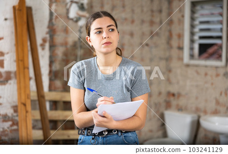 Female architect checking documents in construction site 103241129