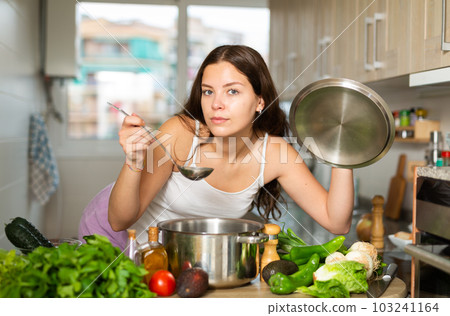 Portrait of young woman cooking at home Portrait of young woman cooking at home 103241164