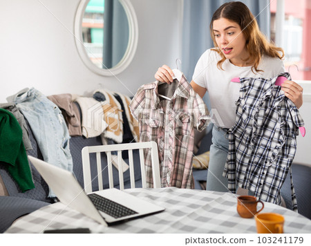 Young woman consults with someone on Internet what clothes to choose 103241179