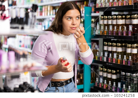 Girl smelling perfume tester in cosmetics store 103241258