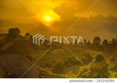 Hazy sunset over green village on the mountain slopes of Merbabu, Central Java, Indonesia. Hazy sunset over green village on the mountain slopes of Merbabu, Central Java, Indonesia. 103242084
