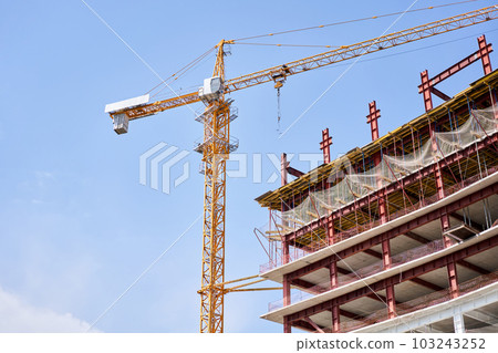 Crane during formworks. Housing renovation concept. View of a large construction site with buildings under construction and multi-storey residential homes.Tower cranes in action on blue sky background 103243252