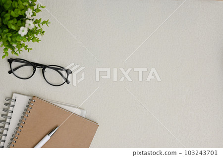 Top view of a grey workspace background with copy space, eyeglasses, books, pen Top view of a grey workspace background with copy space, eyeglasses, books, pen 103243701