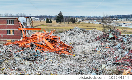 Drone aerial of deconstruction site of abandoned hospital with scrap piles and larger metal scrap pile Drone aerial of deconstruction site of abandoned hospital with scrap piles and larger metal scrap pile 103244344