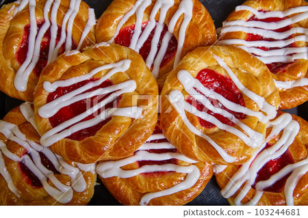 Cherry filled Danish pastry baked good with white frosting zigzagging swirl tray of pastries Cherry filled Danish pastry baked good with white frosting zigzagging swirl tray of pastries 103244681
