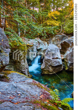 Stunning rocks with river carving gorges by waterfall into blue waters surrounded by mossy forest Stunning rocks with river carving gorges by waterfall into blue waters surrounded by mossy forest 103245060