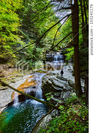 Magical cascading waterfalls through gorge with tourist enjoying view and path of stairs Magical cascading waterfalls through gorge with tourist enjoying view and path of stairs 103245179
