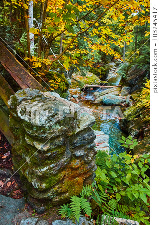 Stone block pillar covered in moss surrounded by fall forest river Stone block pillar covered in moss surrounded by fall forest river 103245417