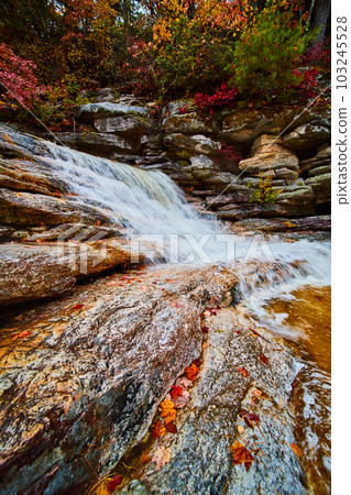 Waterfall up close with exposed rocks and fall leaves Waterfall up close with exposed rocks and fall leaves 103245528