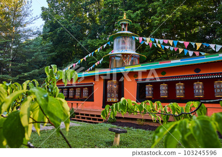 View through leaves of large prayer wheels in temple 103245596