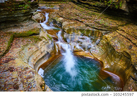 Fall leaves cover terraced rocks in gorge with stunning blue water buckets and waterfalls 103245597