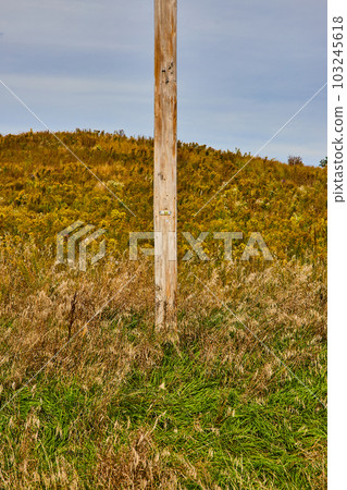 Straight on view of lower half of telephone pole in hilly fields Straight on view of lower half of telephone pole in hilly fields 103245618