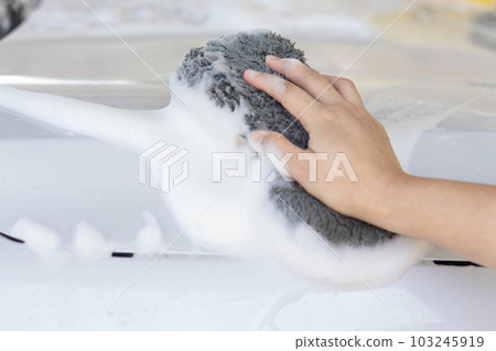 Closeup worker washing white car with sponge on a car wash 103245919