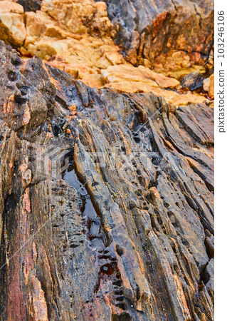 Endless layers of rocks on coast with holes and divots and slots filled with water Endless layers of rocks on coast with holes and divots and slots filled with water 103246106