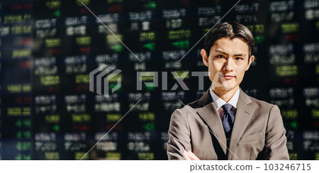 一個男人在電子佈告欄上的股票價格板前雙臂交叉看著相機 103246715