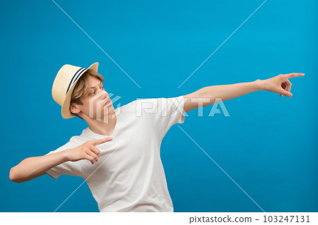 Young teen man points palms aside isolated on blue. Friendly well-looking boy paying your attention at copy space, best deal, sale Young teen man points palms aside isolated on blue. Friendly well-looking boy paying your attention at copy space, best deal, sale 103247131