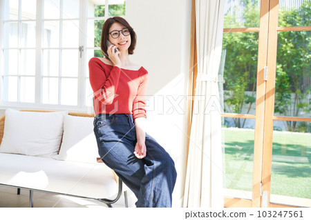 Young woman in plain clothes, living room, smartphone 103247561