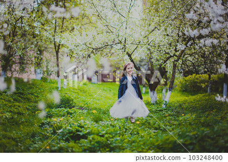Little girl in black jacket and white dress running in the spring cherry garden Little girl in black jacket and white dress running in the spring cherry garden 103248400
