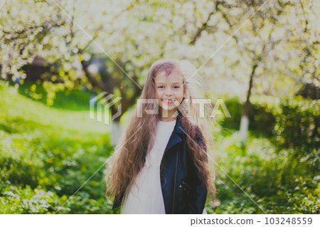 Little girl in black jacket standing in the spring cherry garden Little girl in black jacket standing in the spring cherry garden 103248559