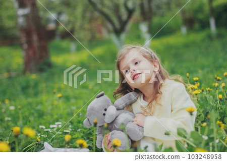 A girl holds a teddy bear in spring cherry garden A girl holds a teddy bear in spring cherry garden 103248958