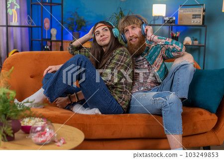 Family man woman in wireless headphones dancing listening favorite rock n roll music on home couch Family man woman in wireless headphones dancing listening favorite rock n roll music on home couch 103249853
