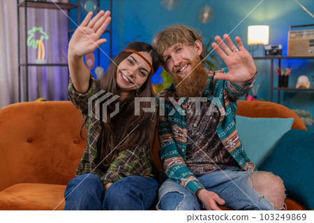 Family man woman smiling friendly at camera, waving hands gesturing hello, hi, greeting at home sofa Family man woman smiling friendly at camera, waving hands gesturing hello, hi, greeting at home sofa 103249869