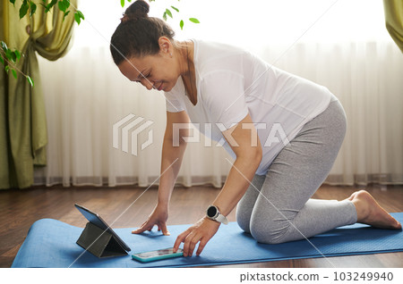 African American adult pregnant woman browsing internet, searching mobile app with yoga and prenatal stretching exercises. Healthy active lifestyle during pregnancy. Easy childbirth. Maternity 103249940