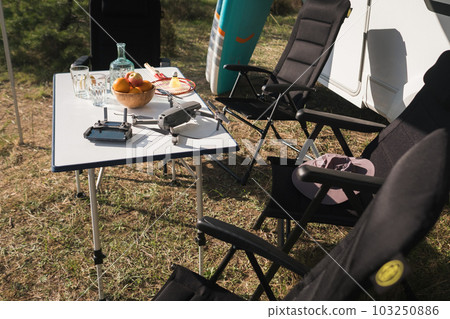 the quadcopter and the remote control are on the table near the campsite 103250886
