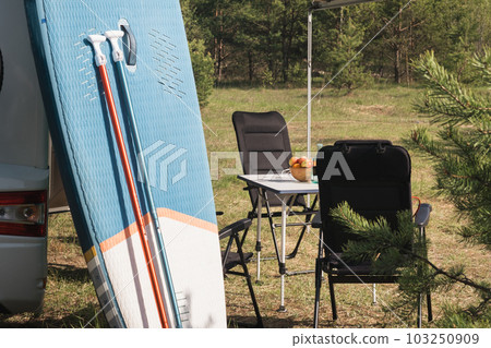 Inflatable Sup rowing boards stand near the motorhome inflated in nature during the day 103250909