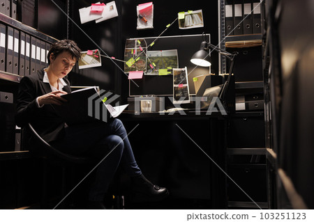 Federal agent holding confidential fbi investigation case files, analyzing crime evidence trying to catch mysterious suspect. Private detective working late at night at discovery in arhive room 103251123
