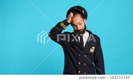 Airline captain raising shoulders and being unsure, shrugging and not knowing answer to question. Young man working as cabin pilot with uniform acting uncertain and clueless on camera. 103251145