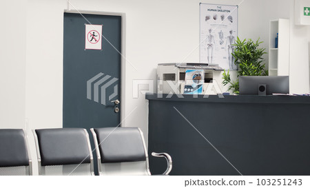 Reception front desk in medical clinic, empty hospital lobby area with chairs and insurance leaflets. Waiting room hallway in emergency facility used for checkup appointments and insurance reports. Reception front desk in medical clinic, empty hospital lobby area with chairs and insurance leaflets. Waiting room hallway in emergency facility used for checkup appointments and insurance reports. 103251243
