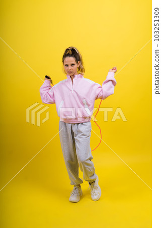 Adorable female child with skipping rope jumping in studio Adorable female child with skipping rope jumping in studio 103251309