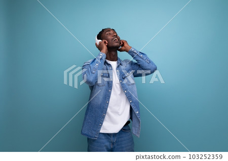 cool dude american man with dreadlocks in a denim jacket relaxes to music in headphones cool dude american man with dreadlocks in a denim jacket relaxes to music in headphones 103252359