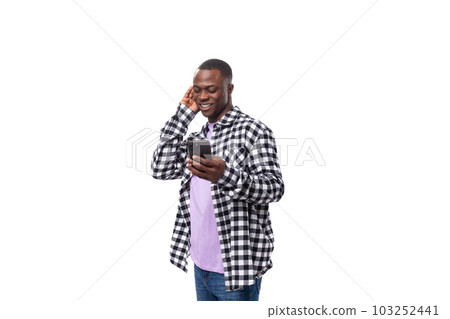 handsome young african man with short haircut in plaid shirt chatting on social network in 103252441