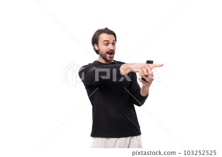 portrait of a European well-built young man with black hair and a beard in a black jacket pointing a 103252525